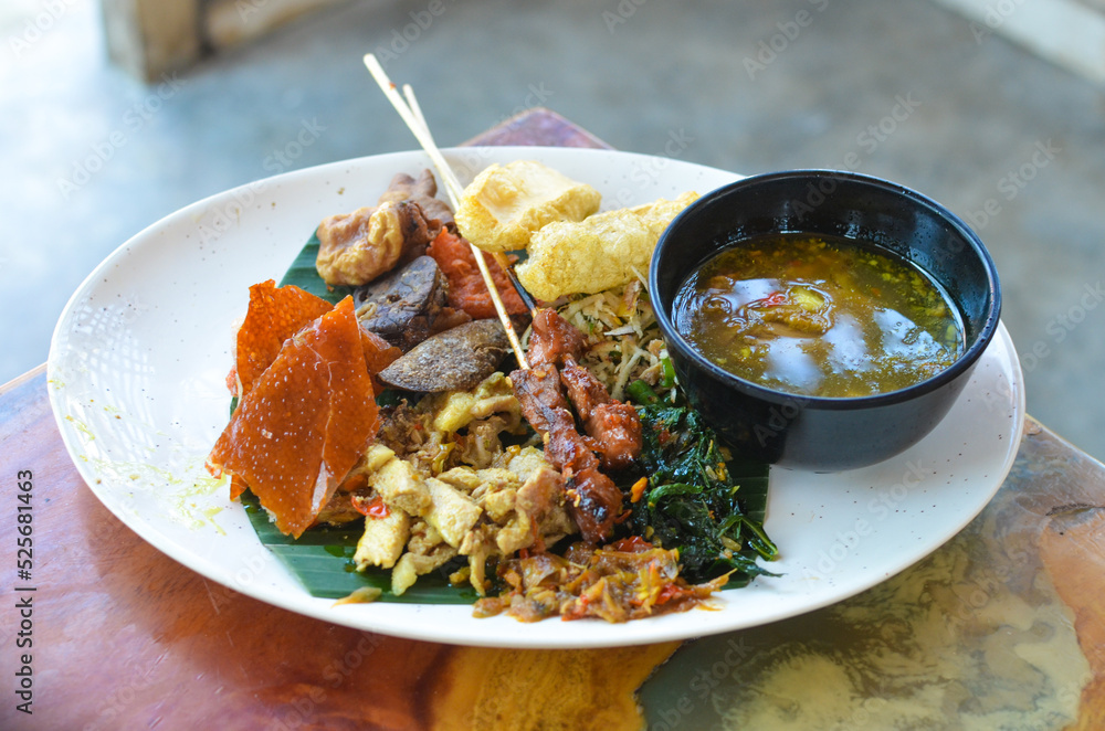 a photo of balinese rice dish of roast pork or usually called nasi campur babi guling with natural light.
