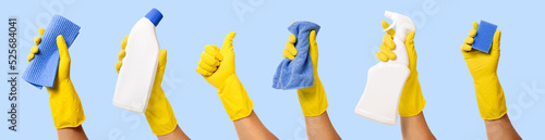 Photos hand with yellow rubber glove holding cleaning supplies on blue background