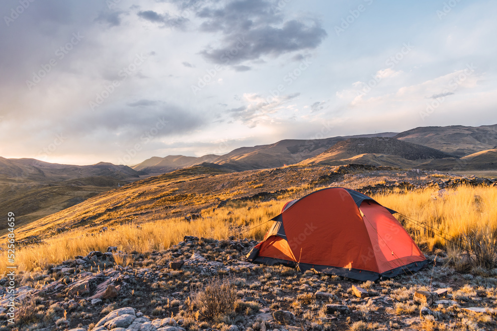 orange colored camp in the mountains in a sunset surrounded by rocks and yellow vegetation in the winter in the andes mountain range