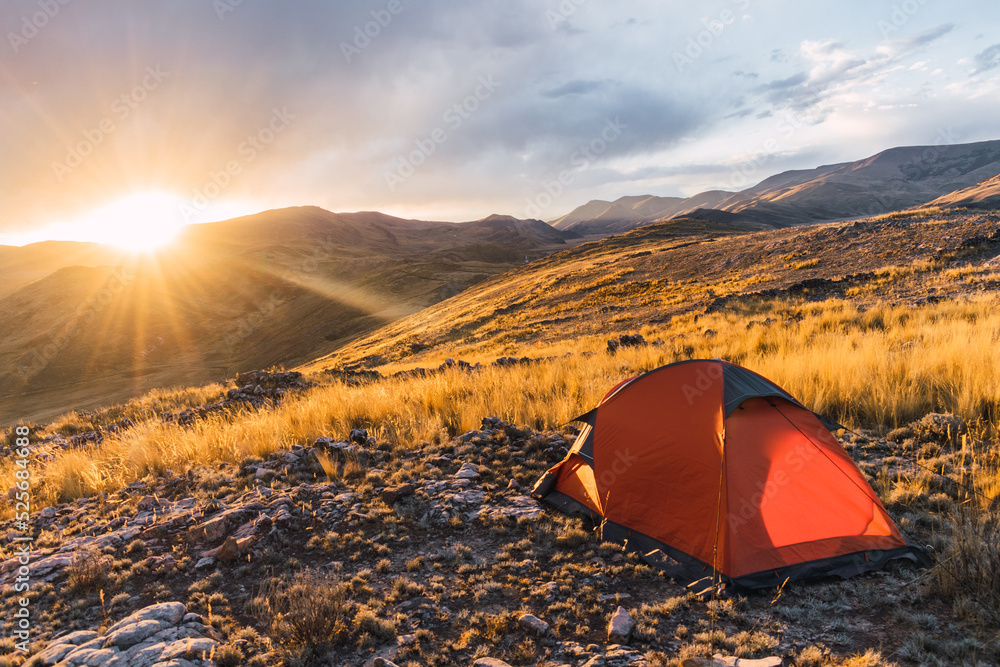 orange colored camp in the mountains in a sunset surrounded by rocks and yellow vegetation in the winter in the andes mountain range