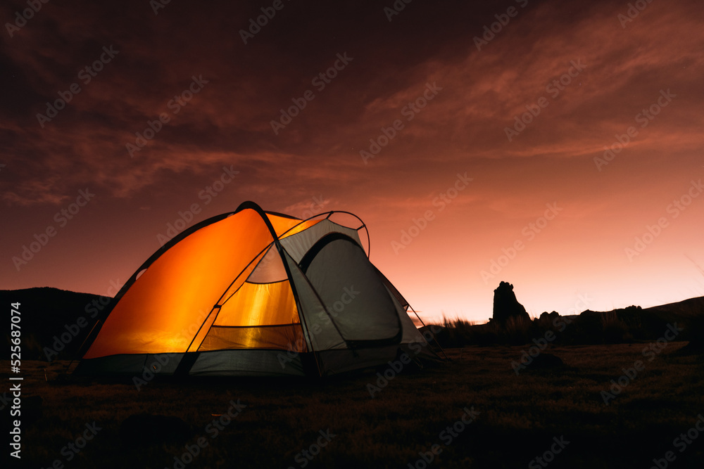 orange colored camp in the mountains in a sunset surrounded by rocks and yellow vegetation in the winter in the andes mountain range