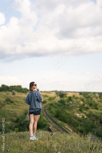 Carefree young woman daydreaming in nature with beautiful clouds in background