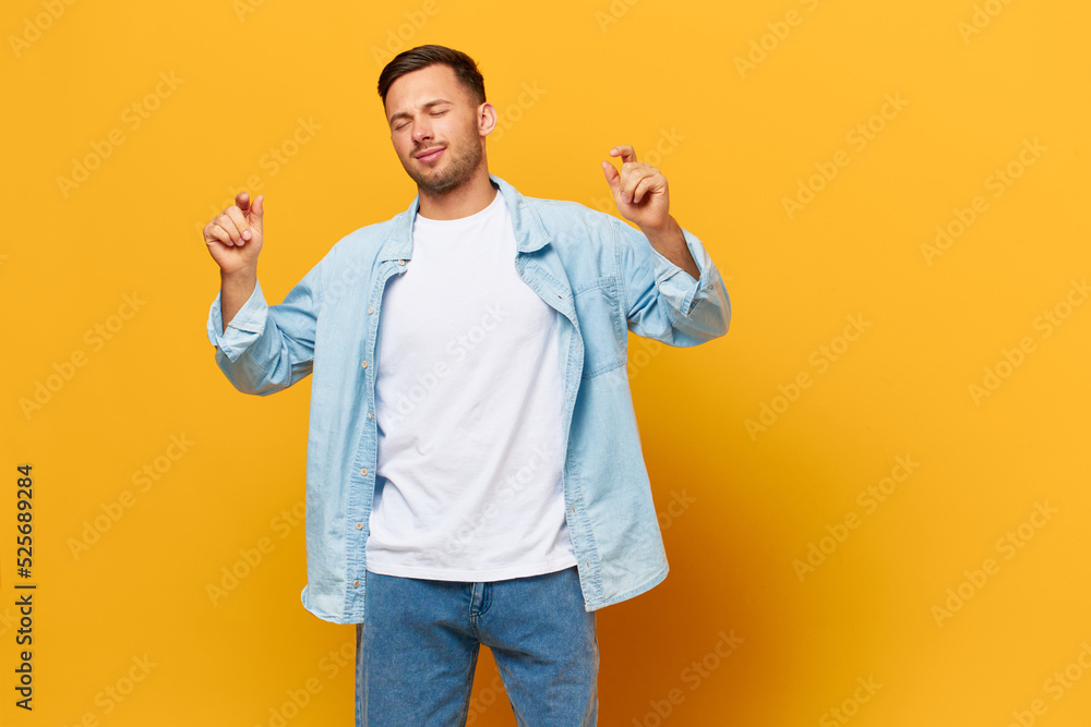 Happy relaxing tanned handsome man in blue basic t-shirt dance enjoy cool day posing isolated on orange yellow studio background. Copy space Banner Mockup. People emotions Lifestyle concept Happy relaxing tanned handsome man in blue basic t-shirt dance enjoy cool day posing isolated on orange yellow studio background. Copy space Banner Mockup. People emotions Lifestyle concept