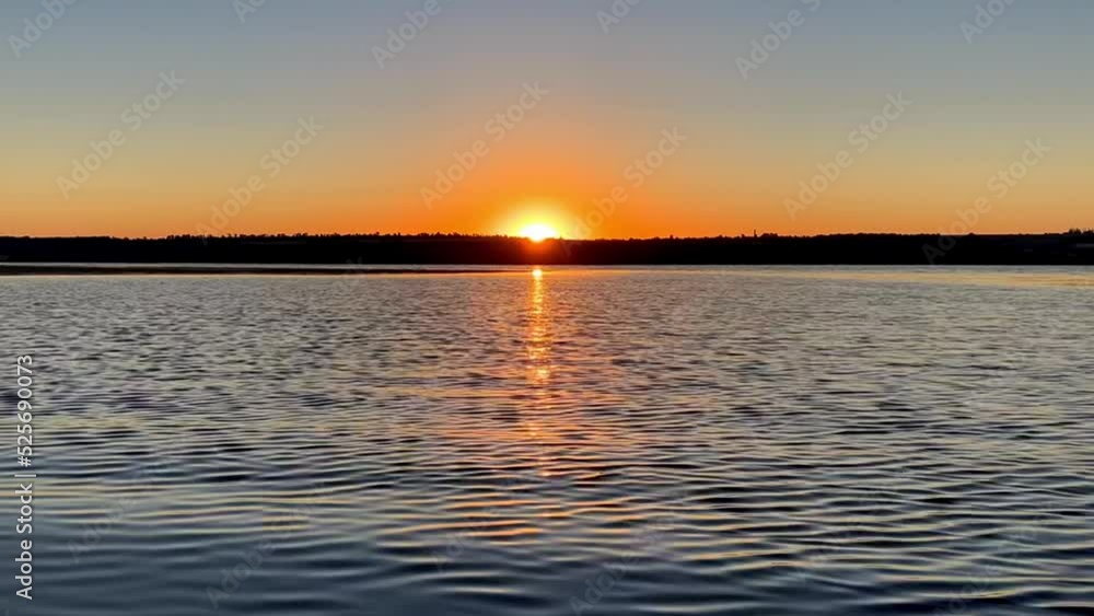 Sunrise over the river near the shore. Rising sun in clear sky. Changeable weather, calm water and waves on the lake. Reflection and glare in the sunlight. Timelapse, 4k. Sunrise over the river near the shore. Rising sun in clear sky. Changeable weather, calm water and waves on the lake. Reflection and glare in the sunlight. Timelapse, 4k.