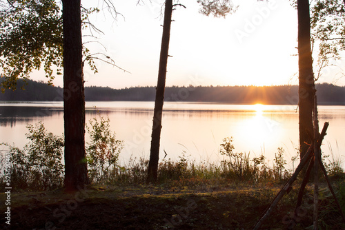 Beautiful view of the forest lake in the early morning with the rising sun and its reflection in the water