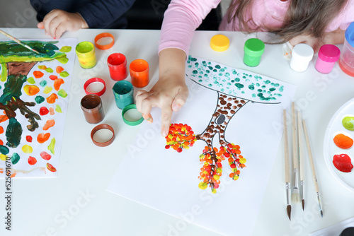 Children draw trees with leaves with colorful paints. Creative activities