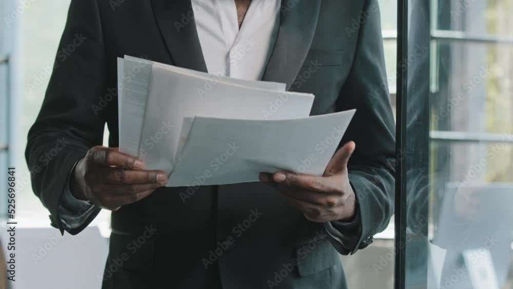 Unknown male businessman teacher boss auditor banker african man in black formal suit stands in office place check financial documents reading paperwork turn sheets banking notification loan insurance Unknown male businessman teacher boss auditor banker african man in black formal suit stands in office place check financial documents reading paperwork turn sheets banking notification loan insurance