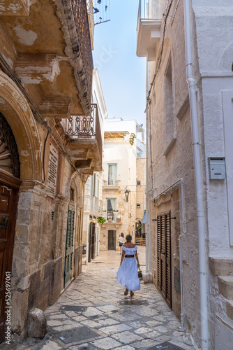 Blonde girl walking near baroque building in Polignano a Mare  Bari  Puglia  Italy.