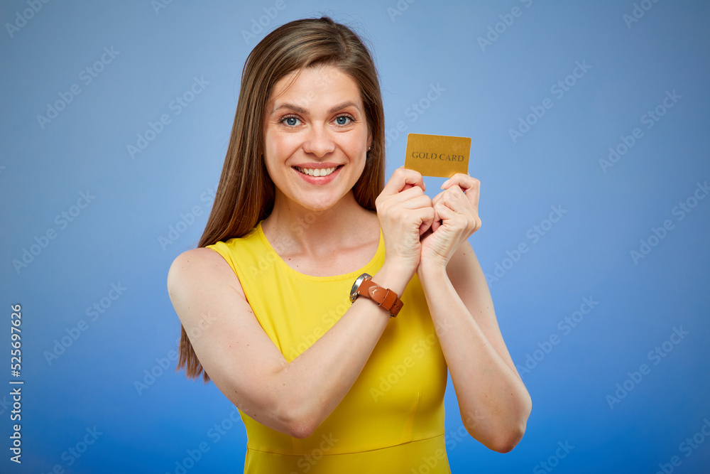 Woman smiling and holding gold credit card. Isolated female portrait on blue background.
