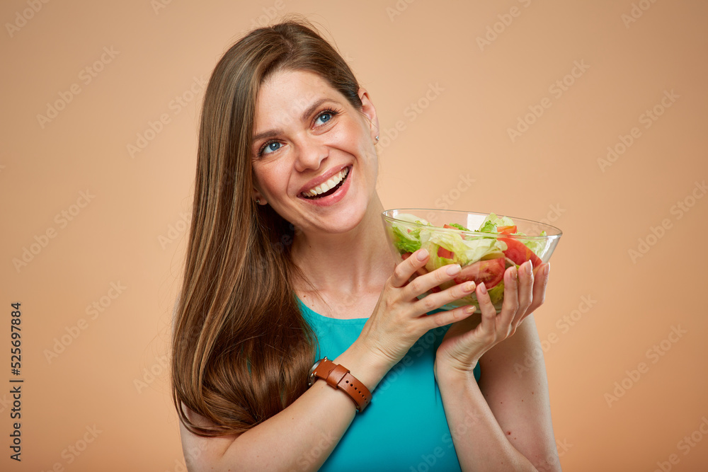 Smiling woman holding salad glass bowl looking up, isolated portrait on yellow brown background. Smiling woman holding salad glass bowl looking up, isolated portrait on yellow brown background.
