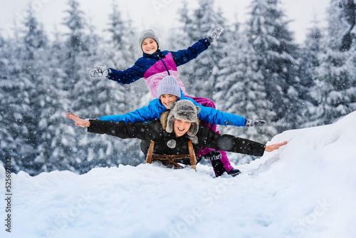 Happy family father, daughter and son are sledding in snow. Happy winter holidays.