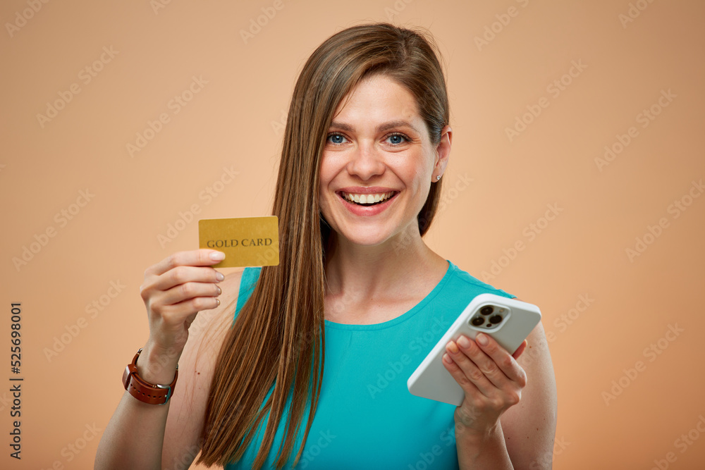 Smiling woman holding credit card and smartphone, isolated portrait on yellow brown background. Smiling woman holding credit card and smartphone, isolated portrait on yellow brown background.
