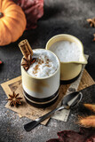 Spicy pumpkin latte or cocoa in ceramic glass with cream and cinnamon. Cozy warm autumn drink concept with pumpkins