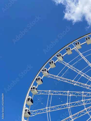 Grande roue sur un fond de ciel bleu dans le Vieux-Port de Montréal. Cabines d'un manège dans un parc d’amusement.