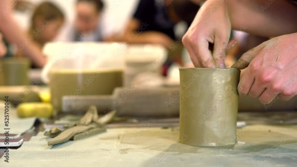 Woman modeling green clay manufacturing a cup, pottery hobby workshop Woman modeling green clay manufacturing a cup, pottery hobby workshop