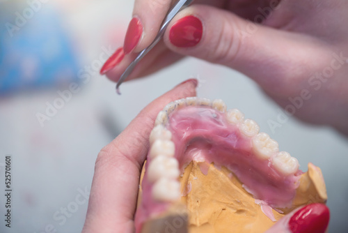 Prosthetics hands while working on the denture, false teeth, a study and a table with dental tools.