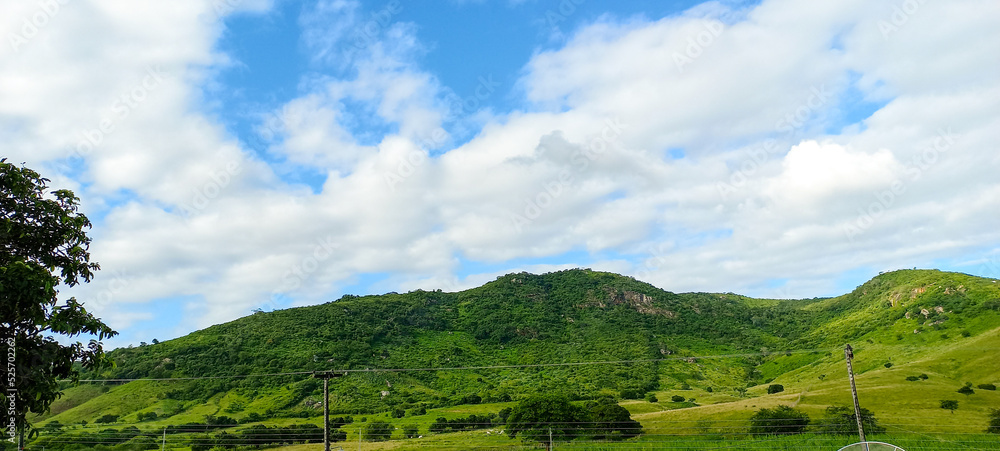 Vista com montanhas com vegetação verdes e um ceú azul no dia de clima tropical e brasileira