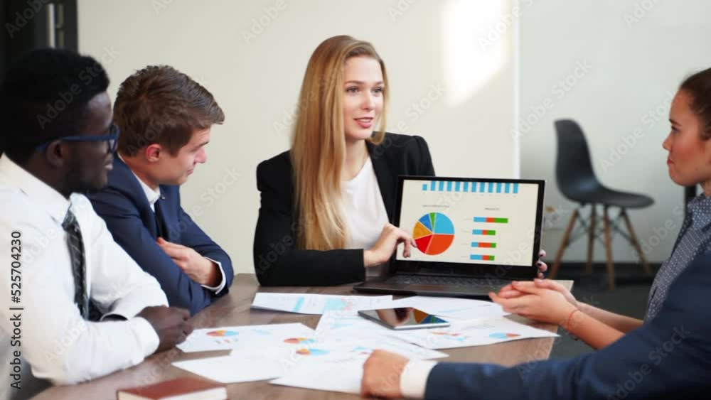 Business woman makes a presentation with charts, diagrams for multiethnic partners. Startup team discuss project plan. Diverse multinational people have meeting in office listening to supervisor. Business woman makes a presentation with charts, diagrams for multiethnic partners. Startup team discuss project plan. Diverse multinational people have meeting in office listening to supervisor.