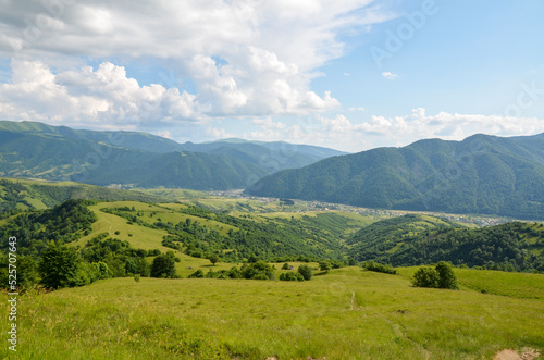 Summer mountain landscape with green rolling hills and the village in the valley in to the distance. Kolochava Transcarpathia, Carpathian Mountains, Ukraine © Dmytro