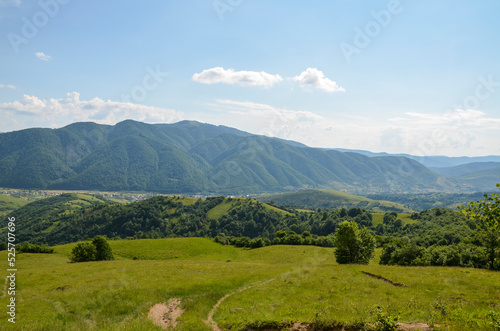 Summer mountain landscape with green rolling hills and the village in the valley in to the distance. Kolochava Transcarpathia, Carpathian Mountains, Ukraine 