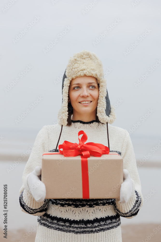 woman in a Santa Claus hat with a gift box in her hands smiles. a happy European woman carries a gift for New Year or Christmas. give gifts and surprises, poster postcard. holiday holidays Christmas woman in a Santa Claus hat with a gift box in her hands smiles. a happy European woman carries a gift for New Year or Christmas. give gifts and surprises, poster postcard. holiday holidays Christmas