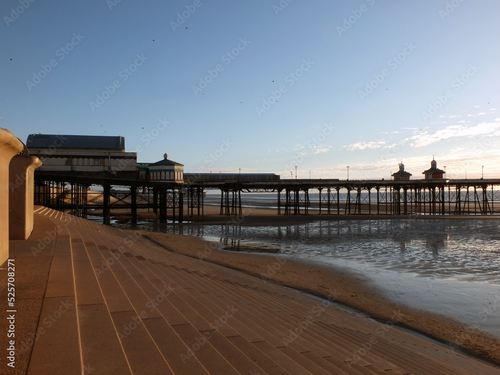 the seawall and steps on blackpool beach at sunset with the north pier reflected on the beach