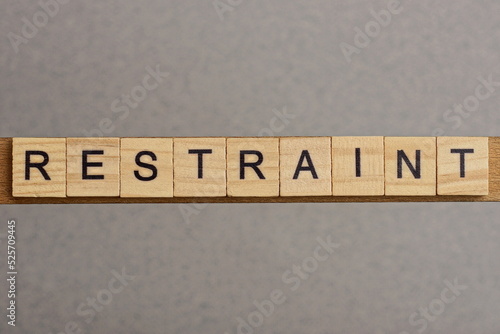 Φωτογραφία text the word restraint from brown wooden small letters with black font on an gr