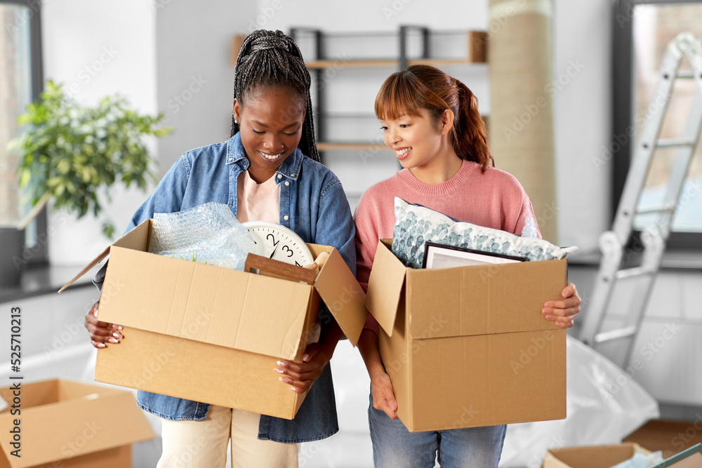 moving, people and real estate concept - happy smiling women with boxes at new home moving, people and real estate concept - happy smiling women with boxes at new home