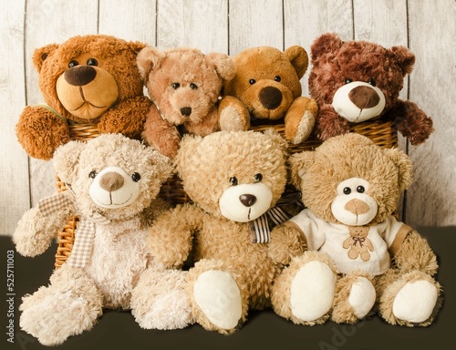 A family of teddy bears sit together in a friendly company on a wooden background. Children's joy soft toys. Photo front close-up, front view.