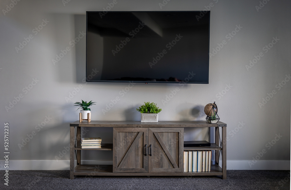Large Flatscreen Television With a TV Stand With Decorations and Gray Wall and Dark Grey Carpet Large Flatscreen Television With a TV Stand With Decorations and Gray Wall and Dark Grey Carpet