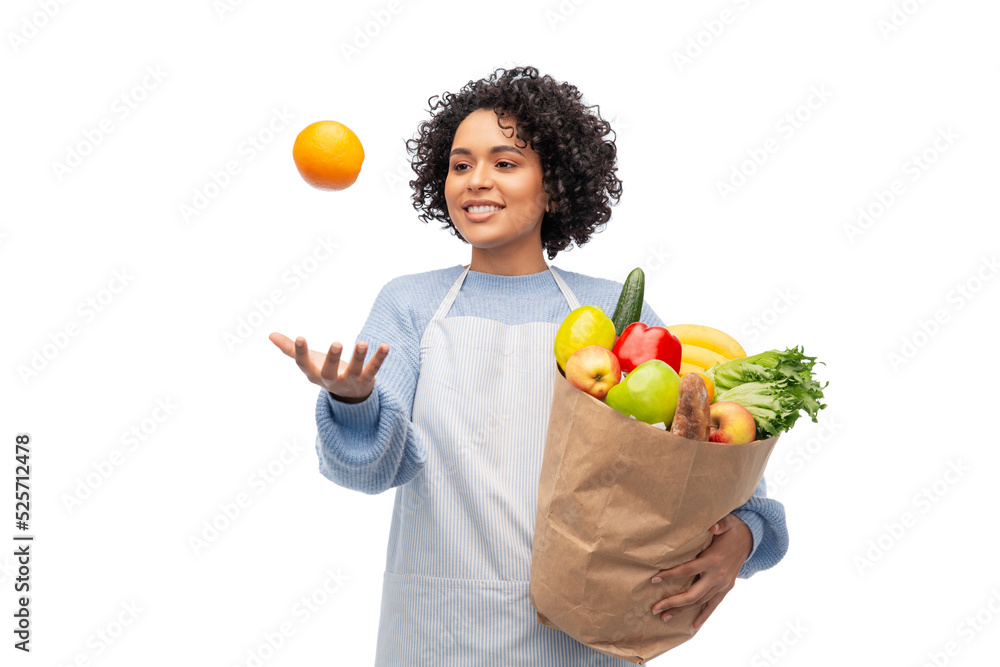cooking, delivery and people concept - happy smiling woman in apron holding takeaway food in paper bag and throwing orange in air over white background cooking, delivery and people concept - happy smiling woman in apron holding takeaway food in paper bag and throwing orange in air over white background