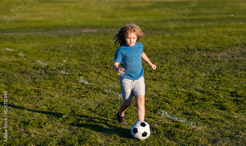 Soccer kid boy playing football. Child boy play football on outdoor field. Children score goal at soccer game. Cute boy kicking soccer ball.