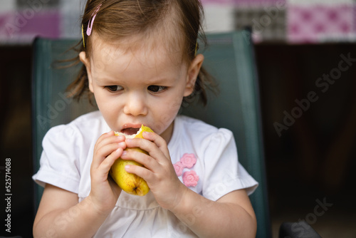 One girl small caucasian toddler child eat pear at outdoor copy space