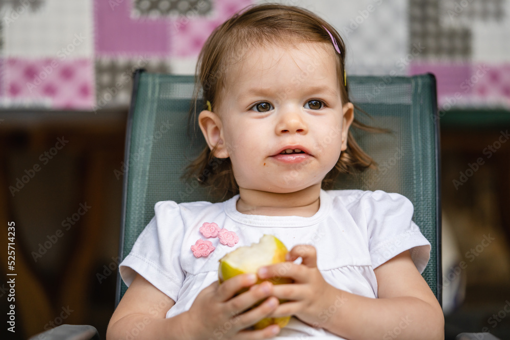 One girl small caucasian toddler child eat pear at outdoor copy space One girl small caucasian toddler child eat pear at outdoor copy space
