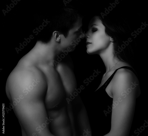 Young couple hugging and kissing as foreplay before having sex isolated on black background	