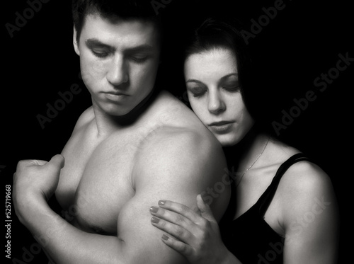 Young couple hugging and kissing as foreplay before having sex isolated on black background 