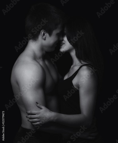 Young couple hugging and kissing as foreplay before having sex isolated on black background 