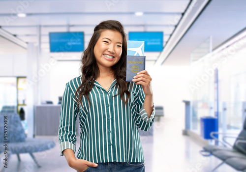 travel, tourism and people concept - happy smiling woman with air ticket and passport over airport background