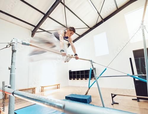 Gymnastics, olympics and sports with a gymnast swinging on a horizontal bar inside of a gym for fitness, training and workout. Sport, exercise and practice with an athlete holding onto parallel bars