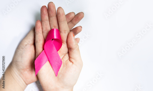 hands holding a pink ribbon on white background, Breast cancer awareness and October Pink day, national cancer survivor day, world cancer day