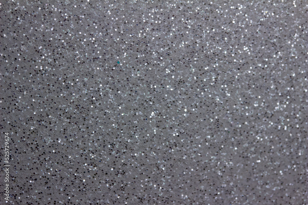 Full frame abstract background of shimmering silver glitter texture with selective focus
