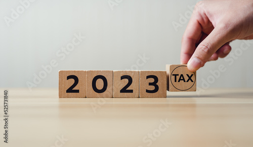 Holding a wooden block with tax 2023. Concept of planning to pay taxes in 2023. paying the tax rate. Taxation, taxes burden.