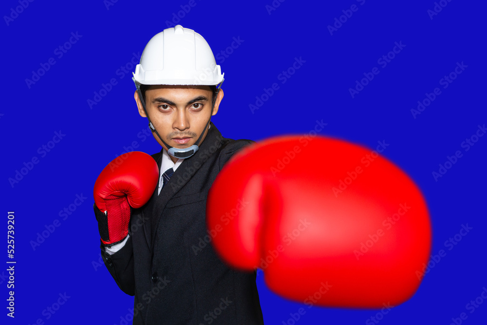 Young Asian Businessman ready to fight in red boxing gloves on blue background, Business competition concept. Young Asian Businessman ready to fight in red boxing gloves on blue background, Business competition concept.