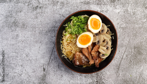 Japanese ramen with pork belly, mushrooms and marinated eggs in a a bowl on a dark grey background. Top view, flat lay