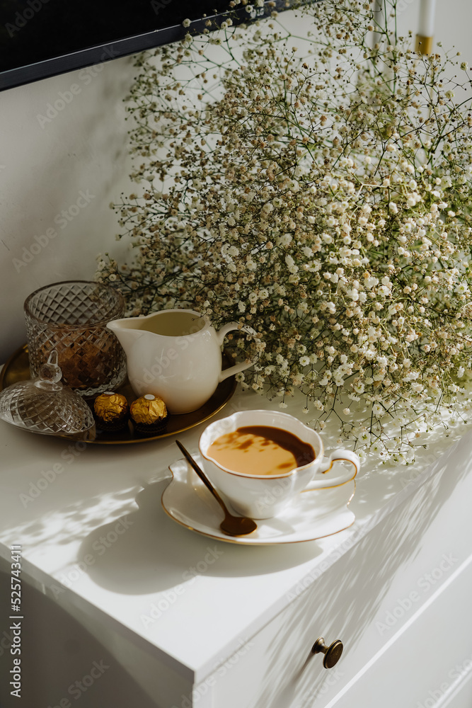 Fototapeta premium A bouquet of flowers, a cup of tea or coffee with milk and sweets on the table. Feels like home comfort and minimalism. aesthetic. 