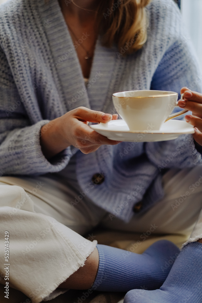 The girl holds in her hands a cup of coffee or tea with milk and a cozy comfortable home atmosphere of relaxation. Aesthetics The girl holds in her hands a cup of coffee or tea with milk and a cozy comfortable home atmosphere of relaxation. Aesthetics