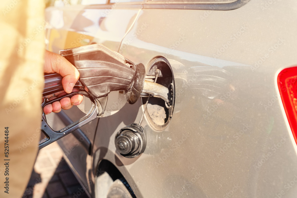 A man at the gas station filling the tank of his car with diesel to the top level before a long journey as fuel prices is going up A man at the gas station filling the tank of his car with diesel to the top level before a long journey as fuel prices is going up