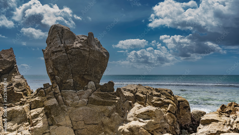 Fototapeta premium Picturesque granite boulders against a background of blue sky, clouds, turquoise ocean. Seychelles. Mahe