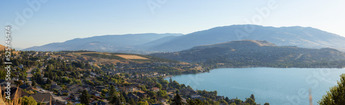 Scenic View of Kalamalka Lake and a small City during sunny summer sunrise. Vernon, British Columbia, Canada. Panorama photo