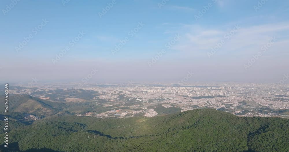 Aerial view of Serra da Cantareira with Sao Paulo in the background. in sunny Brazil - reverse, drone shot Aerial view of Serra da Cantareira with Sao Paulo in the background. in sunny Brazil - reverse, drone shot